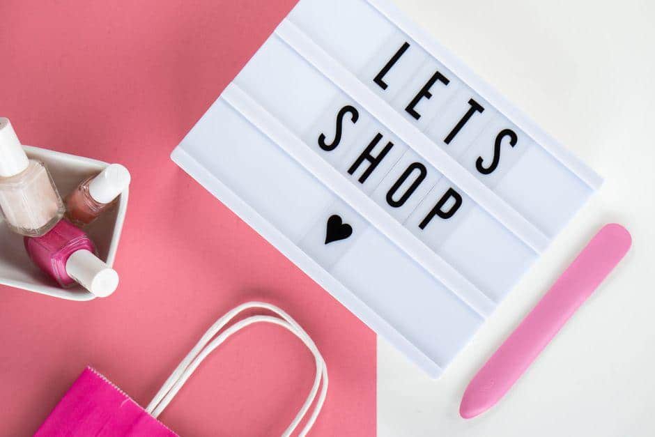 Nail polish bottles and lightbox sign on pink background with shopping bag